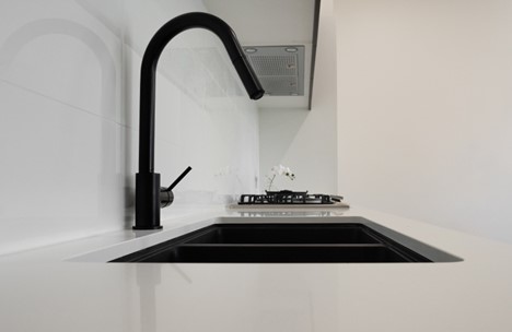 A black faucet over a white countertopDescription automatically generated