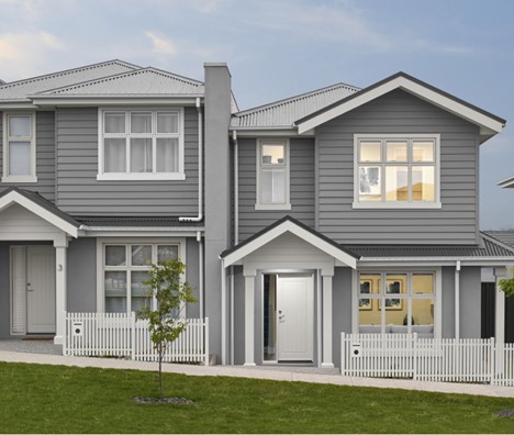 A grey house with a white fenceDescription automatically generated
